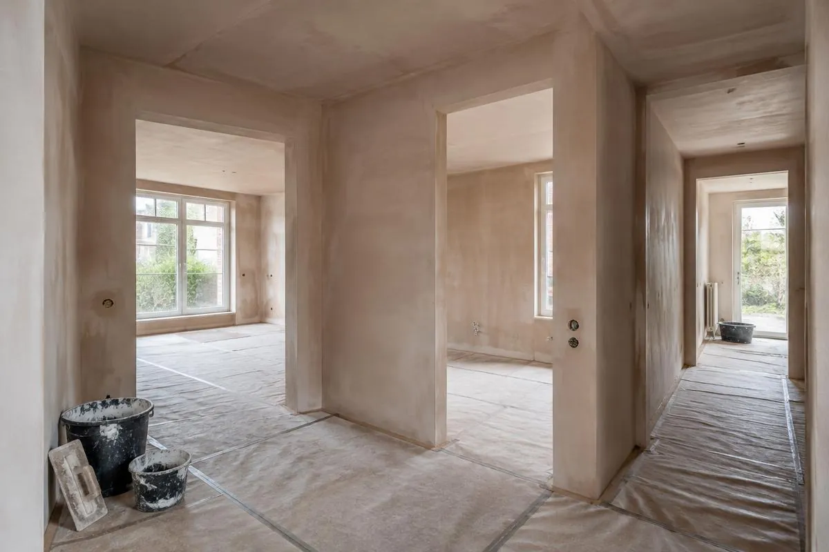 Benedenverdieping in renovatie met vers gestucte wanden en stucloper