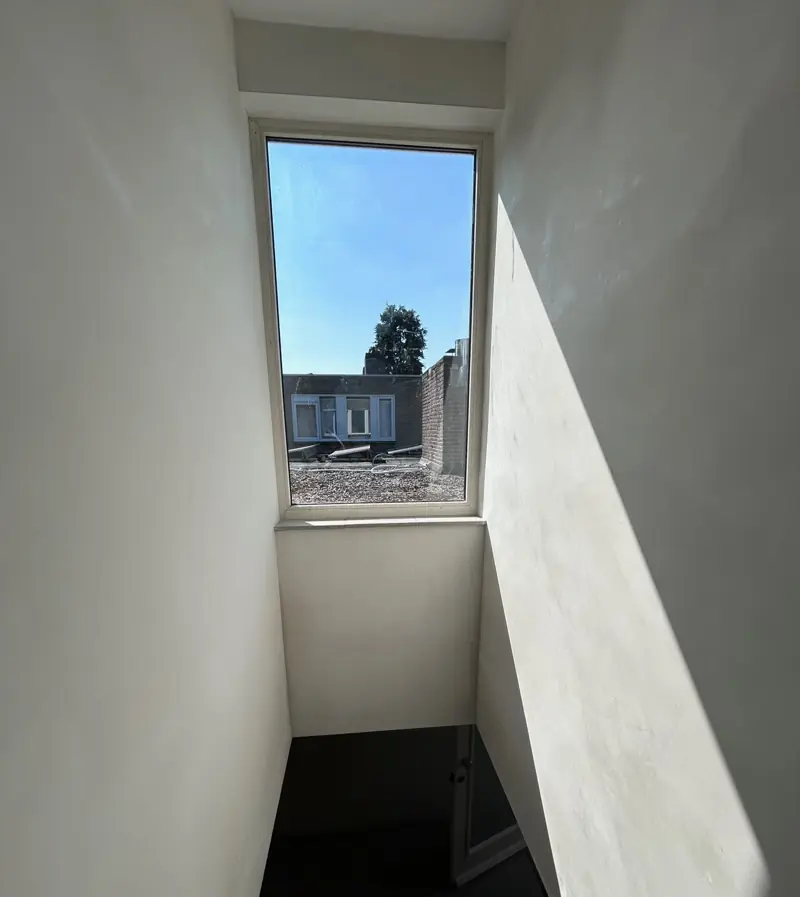 Trapopgang strak gestuct met daglicht door het raam