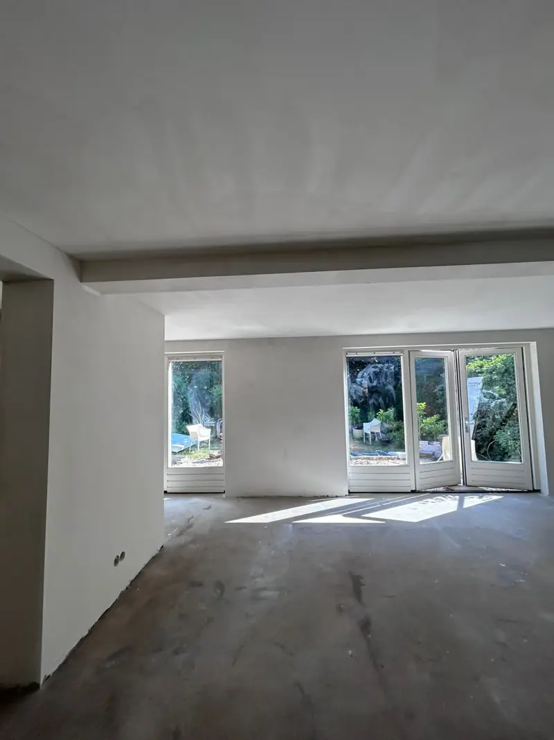 Woonkamer met wanden en plafond strak sausklaar gestuct door SBV Stucadoorsbedrijf